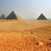 Autokary z turystami pędzą. W oddali, za piramidami, ciemny duszący smog unoszący się nad Kairem.